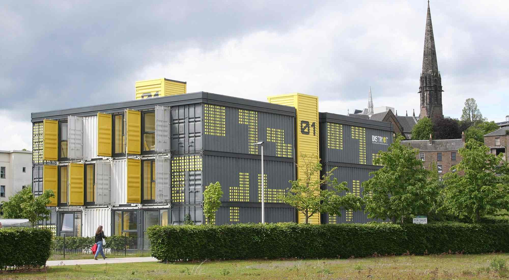 A four-storey modular building clad in yellow and grey panels, finished and occupied